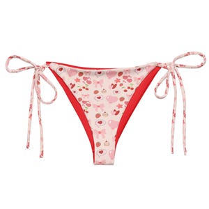 May include: A pink and red reversible bikini bottom with a sweet and playful pattern of hearts, bows, strawberries, and cupcakes. The bikini bottom has adjustable ties on each side.