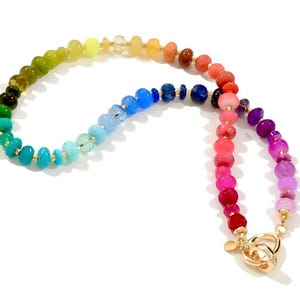 Colorful rainbow gemstone necklace featuring faceted natural stones in bold, vibrant hues with gold accents and a toggle clasp. Handmade statement jewelry displayed on a vanity with soft lighting, highlighting the sparkle and rich texture of each bead. Perfect for stacking or wearing solo.