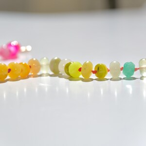 A rainbow multi-gemstone opal necklace that is handknotteded & handcrafted.  Made from natural semi precious opal gemstones.  This necklace is sure to add a pop of color to any outfit. It features a gold dragonfly pendant.