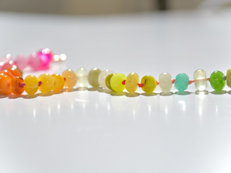 A rainbow multi-gemstone opal necklace that is handknotteded & handcrafted.  Made from natural semi precious opal gemstones.  This necklace is sure to add a pop of color to any outfit. It features a gold dragonfly pendant.