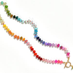 A rainbow multi-gemstone opal necklace that is handknotteded & handcrafted.  Made from natural semi precious opal gemstones.  This necklace is sure to add a pop of color to any outfit. It features a gold dragonfly pendant.