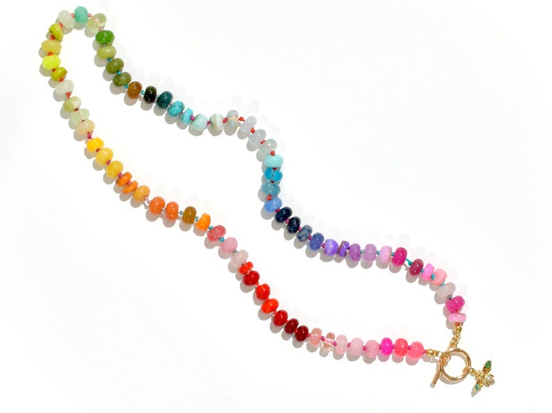 A rainbow multi-gemstone opal necklace that is handknotteded & handcrafted.  Made from natural semi precious opal gemstones.  This necklace is sure to add a pop of color to any outfit. It features a gold dragonfly pendant.