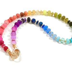 Colorful rainbow gemstone necklace featuring faceted natural stones in bold, vibrant hues with gold accents and a toggle clasp. Handmade statement jewelry displayed on a vanity with soft lighting, highlighting the sparkle and rich texture of each bead. Perfect for stacking or wearing solo.