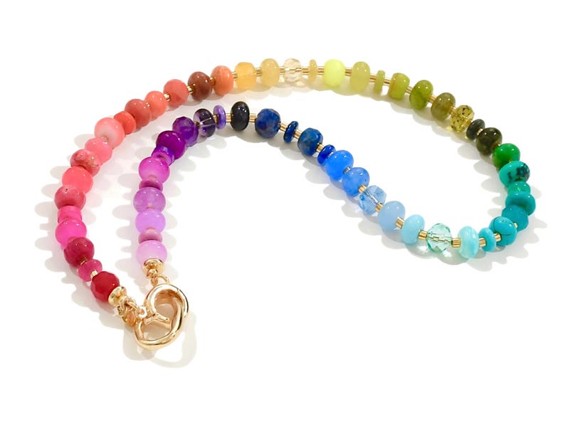 Colorful rainbow gemstone necklace featuring faceted natural stones in bold, vibrant hues with gold accents and a toggle clasp. Handmade statement jewelry displayed on a vanity with soft lighting, highlighting the sparkle and rich texture of each bead. Perfect for stacking or wearing solo.