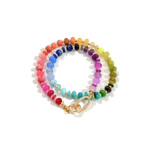 Colorful rainbow gemstone necklace featuring faceted natural stones in bold, vibrant hues with gold accents and a toggle clasp. Handmade statement jewelry displayed on a vanity with soft lighting, highlighting the sparkle and rich texture of each bead. Perfect for stacking or wearing solo.