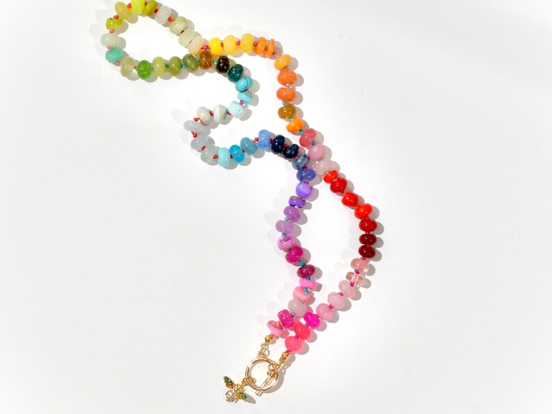 A rainbow multi-gemstone opal necklace that is handknotteded & handcrafted.  Made from natural semi precious opal gemstones.  This necklace is sure to add a pop of color to any outfit. It features a gold dragonfly pendant.