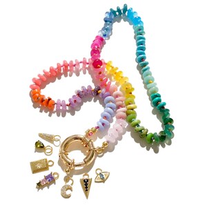 May include: A rainbow colored beaded necklace with a gold clasp and several charms, including a crescent moon, a star, a triangle, and an evil eye.