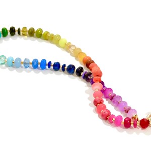 Colorful rainbow gemstone necklace featuring faceted natural stones in bold, vibrant hues with gold accents and a toggle clasp. Handmade statement jewelry displayed on a vanity with soft lighting, highlighting the sparkle and rich texture of each bead. Perfect for stacking or wearing solo.