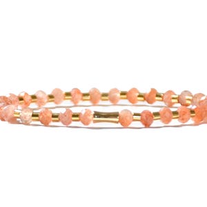 May include: A delicate bracelet made with small, faceted, peach-colored sunstone beads and gold spacers.