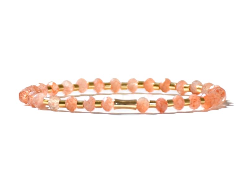 May include: A delicate bracelet made with small, faceted, peach-colored sunstone beads and gold spacers.