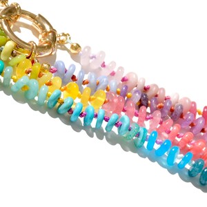 May include: A multi-colored beaded necklace with a gold clasp. The beads are arranged in a rainbow pattern, with each color represented by a different type of stone.