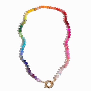 Könnte beinhalten: Eine regenbogenfarbene Perlenkette mit einem goldenen Verschluss. Die Perlen sind in einem Farbverlauf von Gelb nach Rot angeordnet.