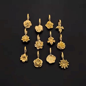 Gold birth flower charm representing each month, featuring a delicate embossed floral design on a round gold pendant — a personalized jewelry gift for her.