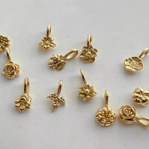 Gold birth flower charm representing each month, featuring a delicate embossed floral design on a round gold pendant — a personalized jewelry gift for her.