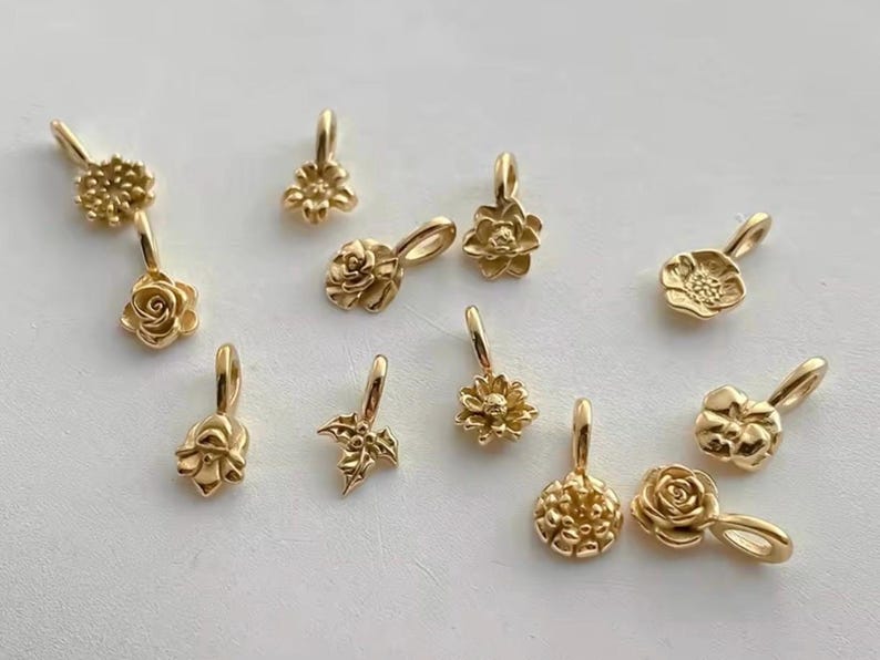 Gold birth flower charm representing each month, featuring a delicate embossed floral design on a round gold pendant — a personalized jewelry gift for her.