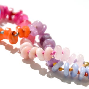 May include: A colorful beaded necklace with pink, orange, purple, and blue beads strung on a pink cord.