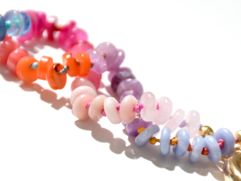 May include: A colorful beaded necklace with pink, orange, purple, and blue beads strung on a pink cord.
