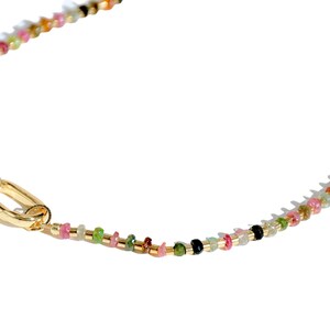 May include: A gold chain necklace with a multi-colored gemstone bead design. The necklace has a lobster clasp closure.