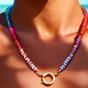 May include: A colorful beaded necklace with a gold clasp. The beads are arranged in a gradient pattern, starting with blue and transitioning to orange.