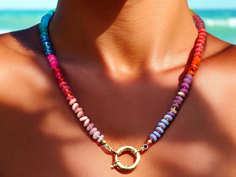 May include: A colorful beaded necklace with a gold clasp. The beads are arranged in a gradient pattern, starting with blue and transitioning to orange.