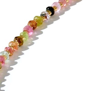 May include: A multi-colored gemstone bead necklace with a gold chain. The beads are in shades of pink, green, brown, and clear.