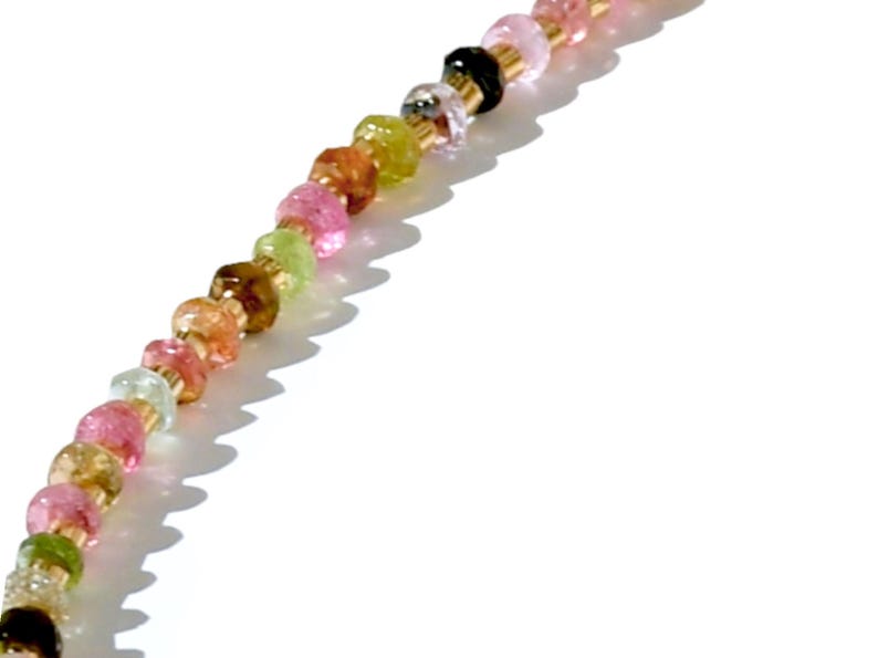 May include: A multi-colored gemstone bead necklace with a gold chain. The beads are in shades of pink, green, brown, and clear.