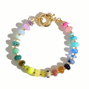 May include: A rainbow gemstone bracelet with a gold clasp. The bracelet features a variety of colourful stones, including pink, blue, green, yellow, and orange.