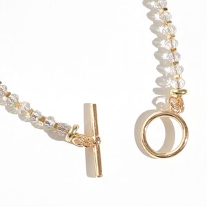 May include: A gold chain bracelet with clear crystal beads and a gold toggle clasp.