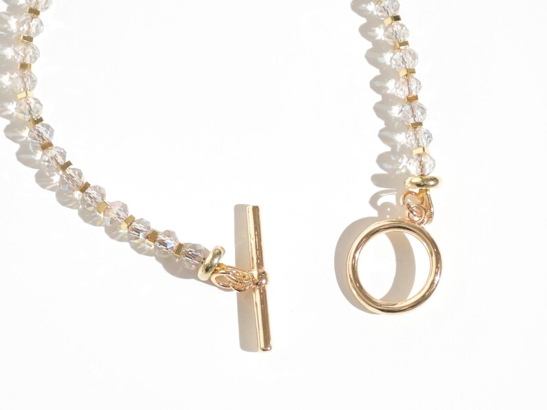 May include: A gold chain bracelet with clear crystal beads and a gold toggle clasp.