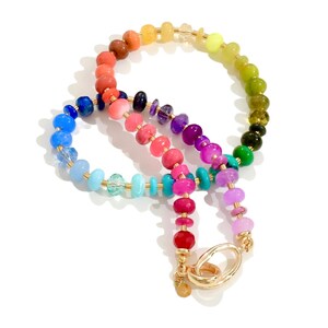 Colorful rainbow gemstone necklace featuring faceted natural stones in bold, vibrant hues with gold accents and a toggle clasp. Handmade statement jewelry displayed on a vanity with soft lighting, highlighting the sparkle and rich texture of each bead. Perfect for stacking or wearing solo.