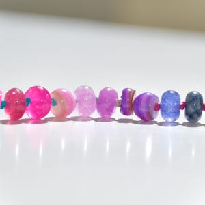 A rainbow multi-gemstone opal necklace that is handknotteded & handcrafted.  Made from natural semi precious opal gemstones.  This necklace is sure to add a pop of color to any outfit. It features a gold dragonfly pendant.