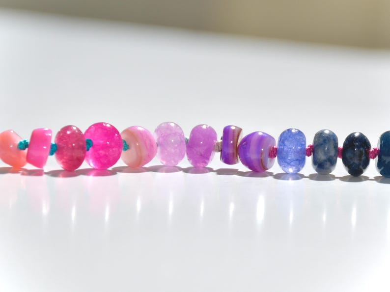 A rainbow multi-gemstone opal necklace that is handknotteded & handcrafted.  Made from natural semi precious opal gemstones.  This necklace is sure to add a pop of color to any outfit. It features a gold dragonfly pendant.