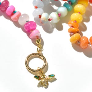 A rainbow multi-gemstone opal necklace that is handknotteded & handcrafted.  Made from natural semi precious opal gemstones.  This necklace is sure to add a pop of color to any outfit. It features a gold dragonfly pendant.