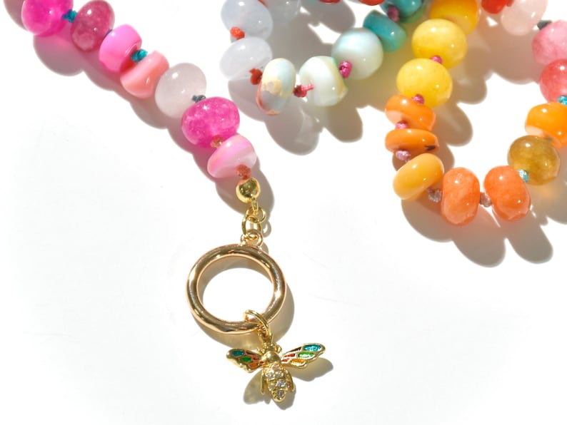 A rainbow multi-gemstone opal necklace that is handknotteded & handcrafted.  Made from natural semi precious opal gemstones.  This necklace is sure to add a pop of color to any outfit. It features a gold dragonfly pendant.
