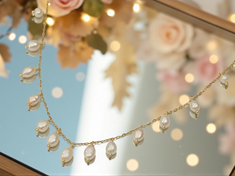 Delicate freshwater pearl necklace with gold chain and dangling pearl drops styled gemininr mirror.