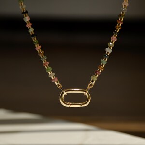May include: A gold chain necklace with a multi-colored gemstone bead design and a gold clasp.