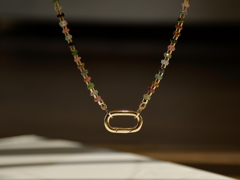 May include: A gold chain necklace with a multi-colored gemstone bead design and a gold clasp.