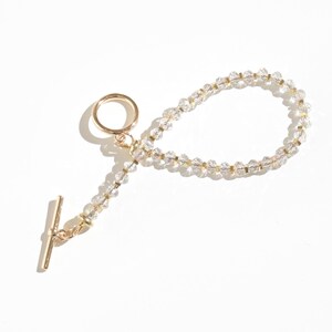 May include: A gold chain bracelet with clear crystal beads and a gold toggle clasp.