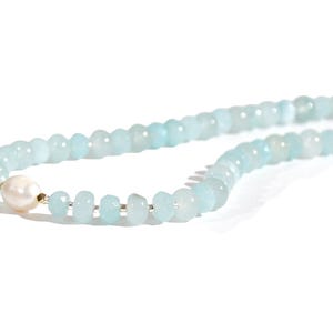 May include: A light blue gemstone necklace with a single white pearl bead.