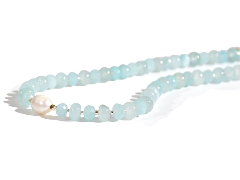 May include: A light blue gemstone necklace with a single white pearl bead.