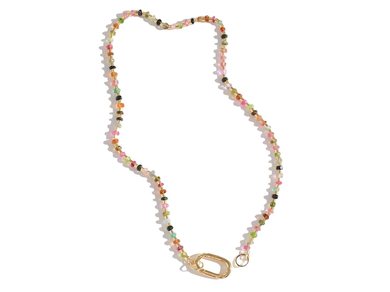 May include: A multi-colored gemstone necklace with a gold clasp. The necklace is made of small, round beads in various shades of pink, green, blue, and black.