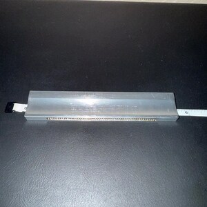 Könnte beinhalten: Ein silbernes Metalllineal mit einem weißen Maßband, das sich von der Seite erstreckt. Das Lineal ist etwa 15 cm lang. Das Maßband zeigt die 15 cm-Marke.