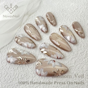 Neutral shimmer nails featuring cat eye gel and floral patterns.