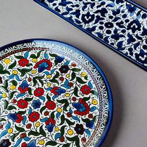 May include: Two ceramic serving dishes with floral patterns. A round plate with a white background and red, blue, and green floral designs. A rectangular tray with a blue and white floral pattern.