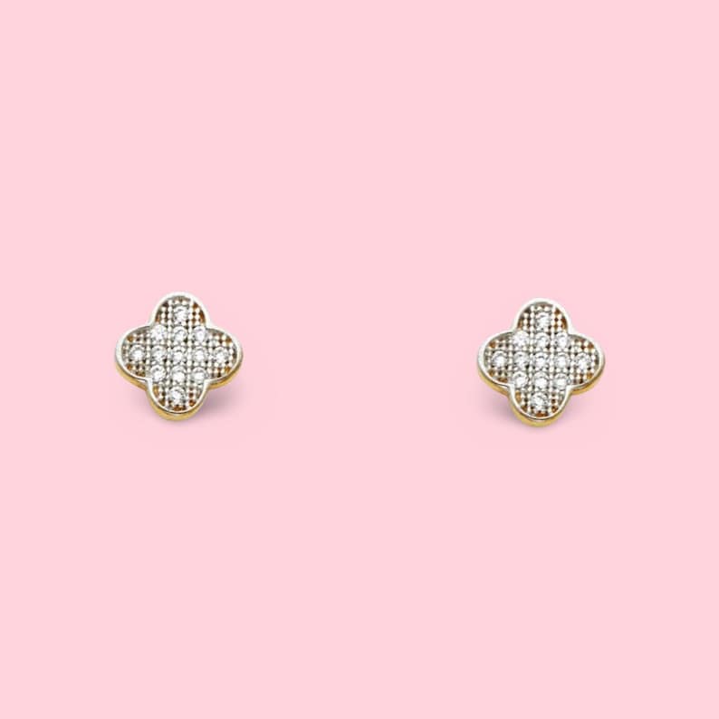 Puede incluir: Un par de pendientes de oro con un dise&ntilde;o de tr&eacute;bol de cuatro hojas, cada hoja est&aacute; incrustada con peque&ntilde;as piedras de circonita c&uacute;bica transparentes.