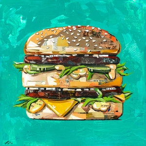May include: A large, multi-layered burger made of paper scraps and magazine clippings. The burger is on a turquoise background. The text "it's warm" is visible on the burger.