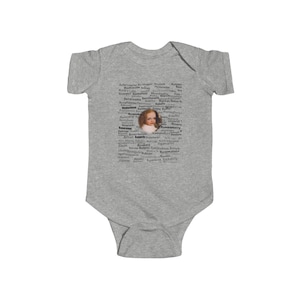Peut inclure: Un body bébé gris avec un design de nuage de mots noir et blanc mettant en scène un portrait d'une jeune fille au centre. Les mots du nuage incluent des noms comme "Rockhopper", "Rumbulberry", "Rockabilly", et "Renegado".