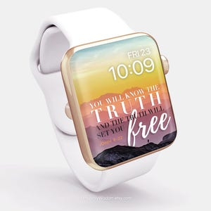 May include: White smartwatch with a gold-colored bezel. The watch face displays the time, date, and the text "YOU WILL KNOW THE TRUTH AND THE TRUTH WILL SET YOU FREE" over a mountain landscape.