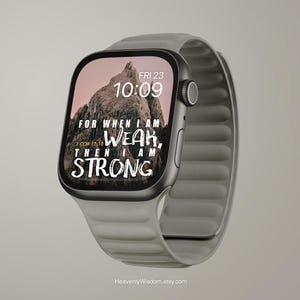 May include: A gray smartwatch with a digital display showing the time, date, and the text "FOR WHEN I AM WEAK, THEN I AM STRONG." The watch has a gray band and a black bezel. The screen displays a mountain image.