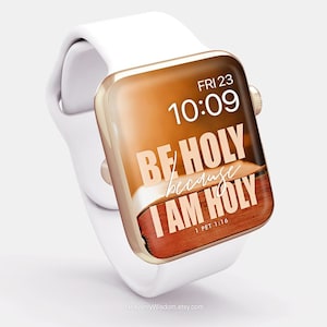 Op de afbeelding: Een witte Apple Watch met een gouden band en een bruin en gouden wijzerplaat. De wijzerplaat toont de tijd 10:09, de dag FRI 23 en de tekst "BE HOLY because I AM HOLY 1 PET 1:16".